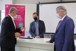 Helge Frisch (von links) von der Deutschen Telekom erklärt Schulleiter Steffen Heerwagen und Landrat Thomas Fügmann anhand eines Modells die Vorteile eines Glasfaseranschlusses.