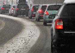 Pkw auf schneebedeckter Straße in Stausituation