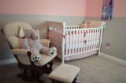 Blick in ein Kinderzimmer mit einem kleinen Sessel samt Teddybär und einem Gitterbett (Symbolfoto).