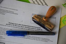 Papierakten werden im Landratsamt Saale-Orla-Kreis zum Auslaufmodell. Das Foto zeigt einen ausgedruckten Antrag aus dem Schwerbehindertenrecht samt Stift und Stempel.