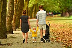 Eine Familie beim Spaziergang mit Kinderwagen (Symbolfoto)