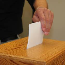 Haben Sie Ihre Wahlbenachrichtigung schon erhalten? © Mandy Käßner / Landratsamt Saale-Orla-Kreis Eine Hand steckt einen Stimmzettel in eine Wahlurne (Symbolfoto).