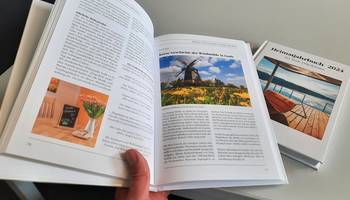 Ein aufgeschlagenes und ein zugeklapptes Exemplar des Heimatjahrbuchs von 2024. Es erschien unter dem Titel „Erholen und Genießen im Saale-Orla-Kreis“. Das Leitthema der nächsten Auflage lautet „Landschaften und Orte im Wandel“.