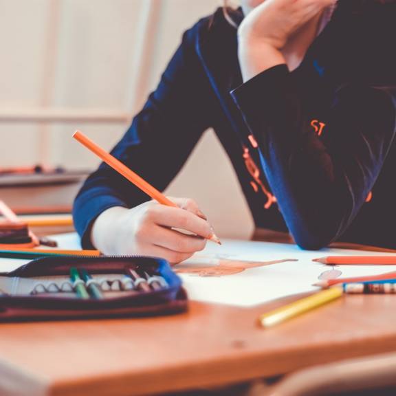 Schüler schreibt an einem Tisch Schüler schreibt an einem Tisch