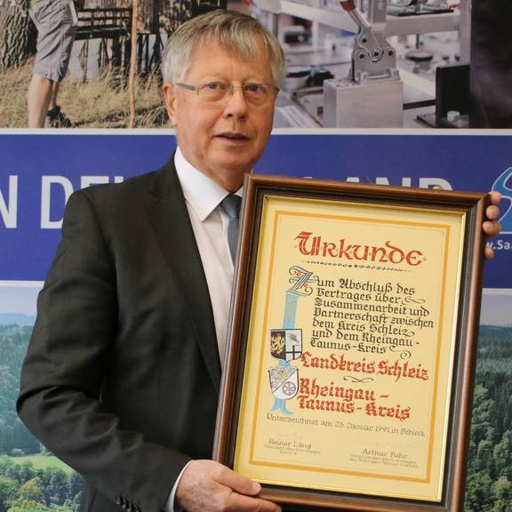 Seit 30 Jahren besteht die Partnerschaft mit dem Rheingau-Taunus-Kreis © Pressestelle Landratsamt / Alexander Hebenstreit Saale-Orla-Landrat Thomas Fügmann mit der Urkunde zum Abschluss der Partnerschaft zwischen dem ehemaligen Landkreis Schleiz und dem Rheingau-Taunus-Kreis. Mit der Entstehung des Saale-Orla-Kreises 1994 wurde die Partnerschaft erneuert.