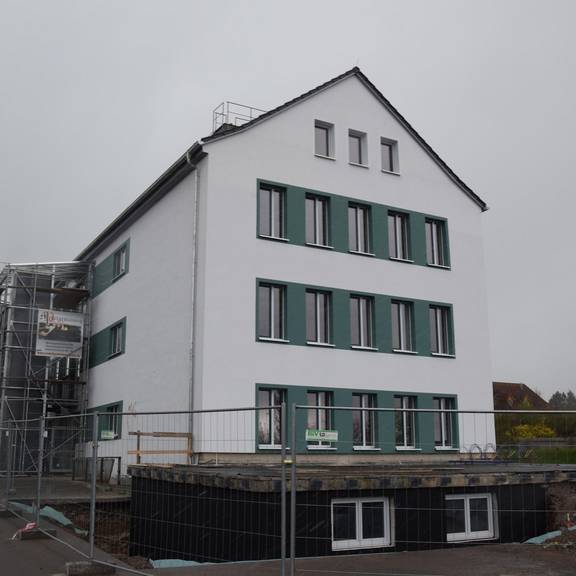 Schulgebäude weiß mit petrolfarbenen Fenstern und Elementen