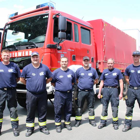 Sechs Feuerwehrleute vor Fahrzeug Dekon P