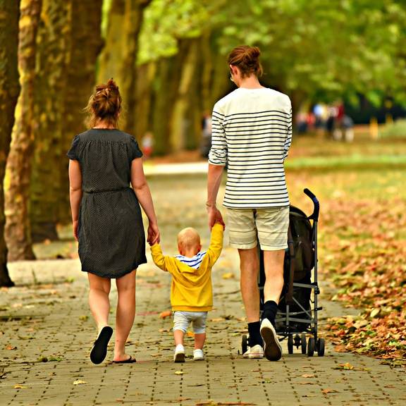 Eine Familie beim Spaziergang mit Kinderwagen (Symbolfoto)