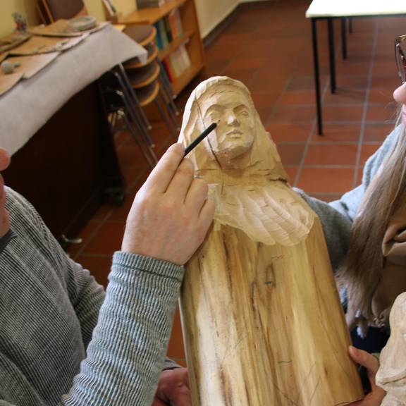 zwei Personen mit Holzfigur