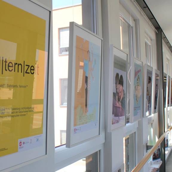 Im unteren Foyer des Landratsamtes sind als Teil der Ausstellung „Väter heute – neue Väter“ Plakate zu sehen, die sich dem Thema künstlerisch auf ganz unterschiedliche Weise – von ganz nüchtern bis ironisch – annähern.