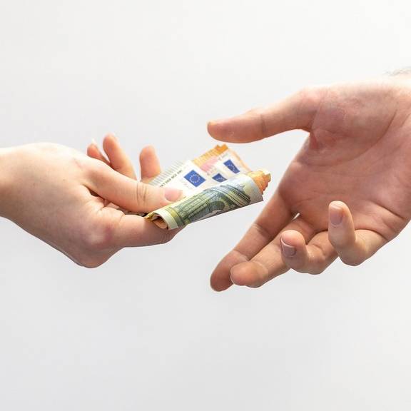 Eine Hand reicht einer anderen Geldscheine (Symbolfoto).